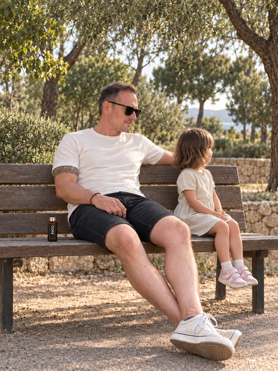 Un père partage un moment avec son enfant sur un banc, une bouteille CORE près de lui.